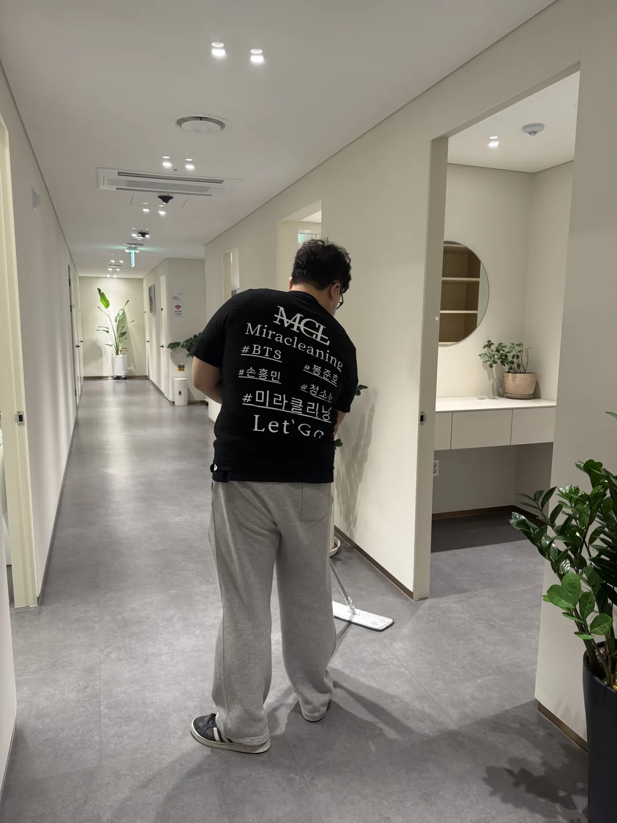 공용 복도를 밀대로 습식 청소하는 작업자